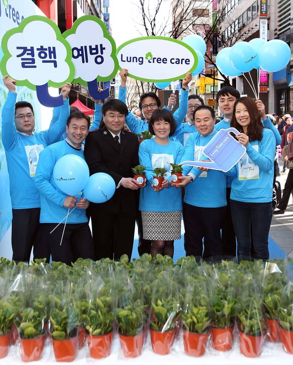 한국얀센 김옥연 대표이사(가운데)와 임직원 및 대한결핵협회, 구세군 관계자들이 서울 명동예술극장 앞에서 결핵 예방과 인식향상을 위한 ‘Lung Tree Care’ 캠페인을 알리며 건강한 폐와 강인한 생명력을 뜻하는 청페페 화분을 나눠주고 있다.