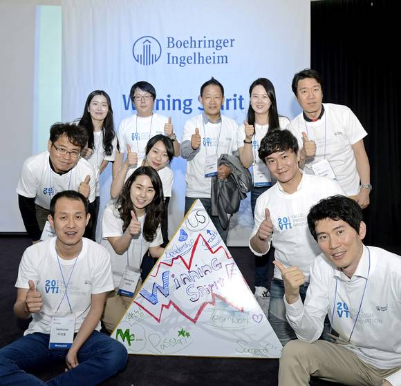 혁신과 승리에 대한 아이디어가 그려진 피라미드를 완성하고 화이팅을 외치고 있는 한국베링거인겔하임 직원들