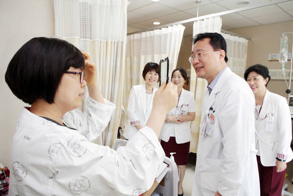 고려대 안암병원 호스피스회장 박종훈 교수(사진 우측)가 안재욱씨가 전달한 가발을 암환자에게 씌워주며 환하게 웃고 있다