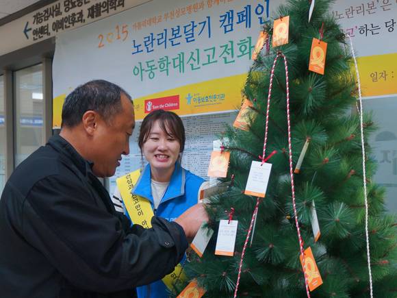 부천성모병원을 찾은 내원객이 아동학대예방을 위한 서명운동에 참여하고, 아동학대 발견시 신고하겠다는 의미의 노란리본을 달고 있다.