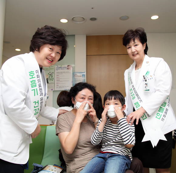 유경하 이대목동병원장(사진 오른쪽)과 박은애 이화의료원 기획조정실장(사진 왼쪽)이 이대목동병원 소아청소년과 외래에 방문한 엄마와 아이에게 황사마스크 사용법을 알려주고 있다.