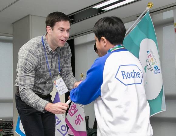 매트 사우스 ㈜한국로슈 대표이사가 조 대표 어린이에게 조 깃발을 수여하며 환영하고 있다.