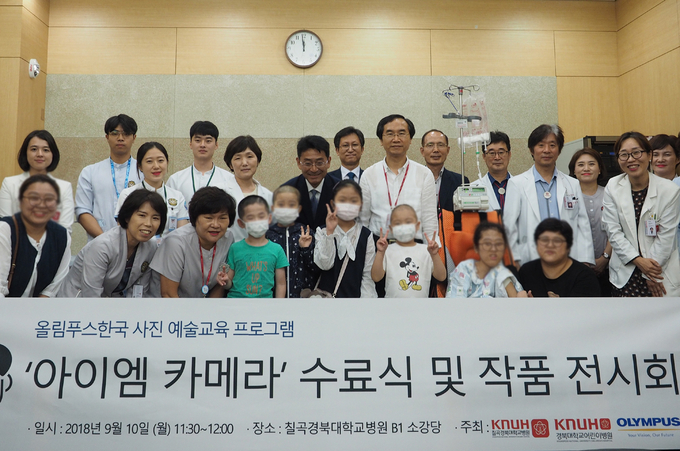 환아들과 가족, 오카다나오키 올림푸스한국 사장(뒷줄 왼쪽에서 6번째), 권순학 칠곡경북대학교병원 어린이병원장(뒷줄 왼쪽에서 8번째)을 비롯한 관계자들