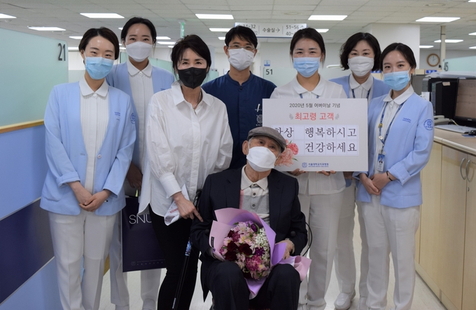 어버이 날 치과보존과를 내원한 최고령 환자에게 꽃다발을 증정하고 있다.