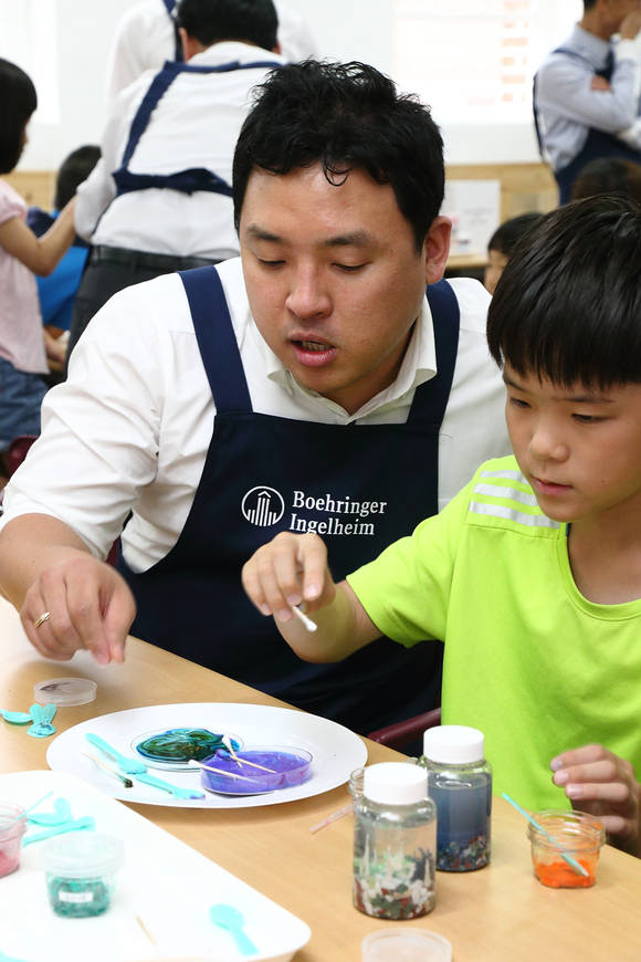 한국베링거인겔하임 임직원 봉사단과 아동복지원 혜심원 및 용산지역 아동센터 아동들이 ‘꿈꾸는 과학교실’에서 우유 속 지질성분을 활용해 그림을 그리며 화학 원리를 배우고 있다.